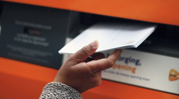 closeup van een brief die in een brievenbus wordt gedaan