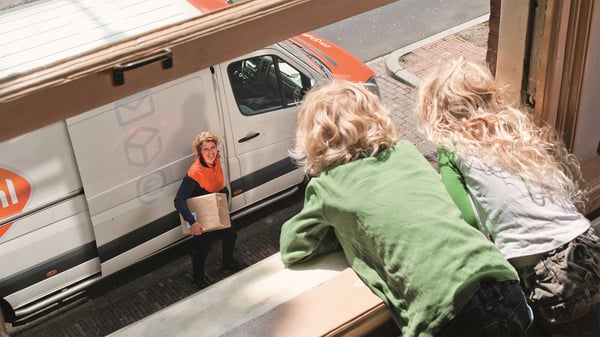 Pakketbezorger met kinderen hangend uit het raamkozijn