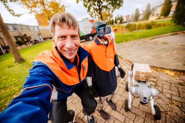PostNL-bezorger maakt een selfie met een bezorgrobot naast zich in een woonwijk.
