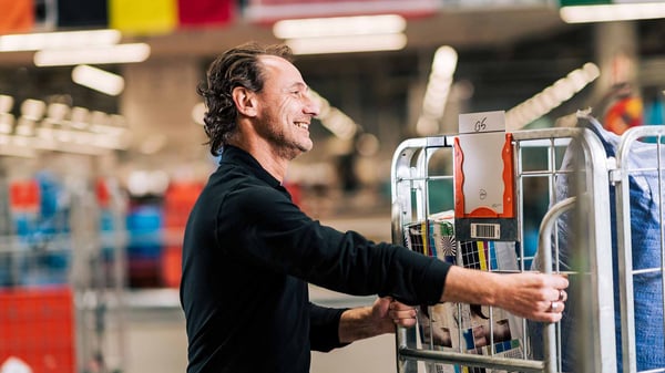 Sorteercentrummedewerker duwt in een sorteercentrum een container vol internationale pakketten