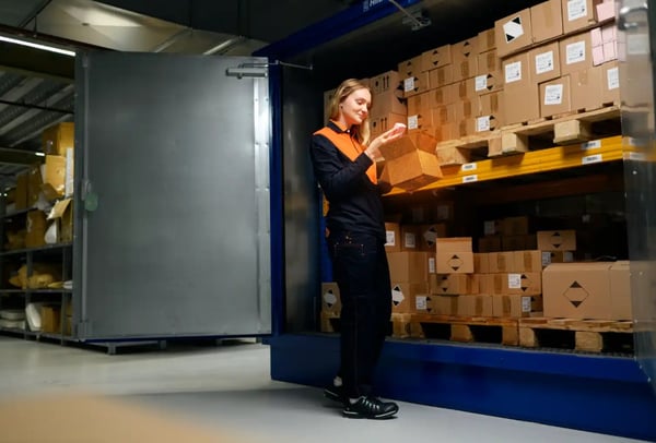 Magazijnmedewerker controleert een doos tussen pallets met pakketten in een depot.