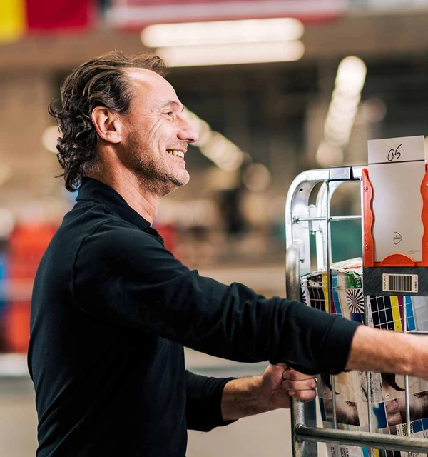 Sorteercentrummedewerker duwt in een sorteercentrum een container vol internationale pakketten